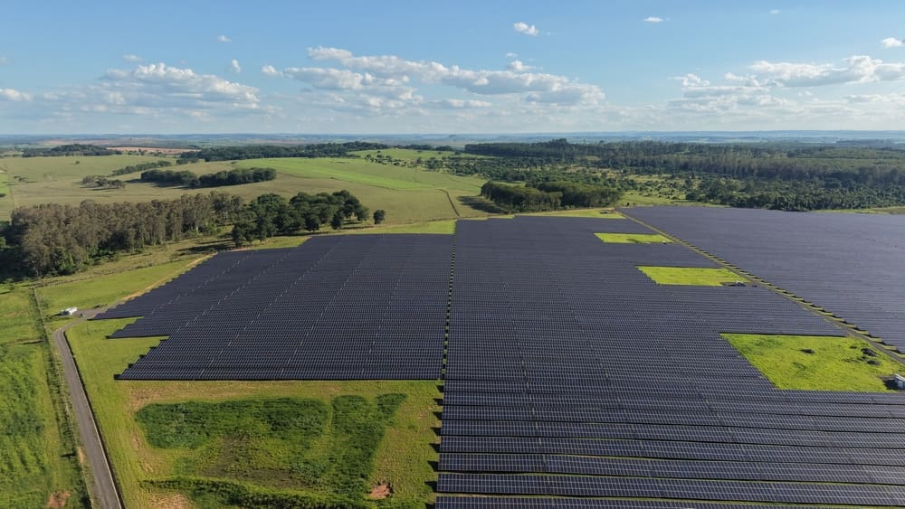 Aerial view of a large solar panel farm surrounded by green fields